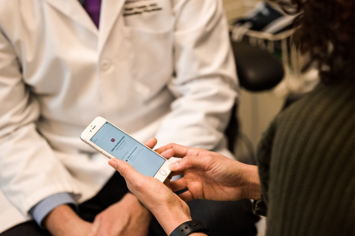 Woman sitting with a doctor and checking her phone