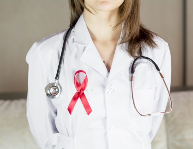 Female doctor with red HIV, world AIDS day awareness ribbon.