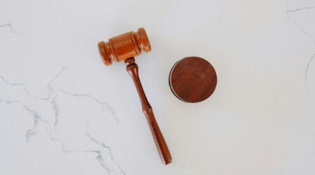 A wooden gavel on a white marble backdrop